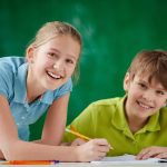 Portrait of cute schoolkids looking at camera while drawing at lesson