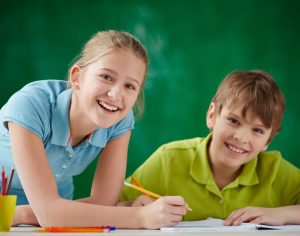 Portrait of cute schoolkids looking at camera while drawing at lesson
